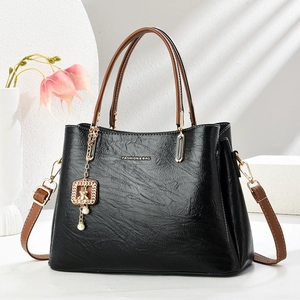 Retro black leather tote with brown handles and a gold bear charm pendant