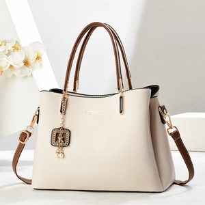Chic cream leather tote bag with brown handles and a gold bear charm for women