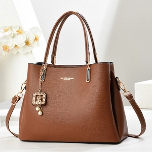 Fashionable brown pebble leather tote bag with gold hardware and pearl charm on display