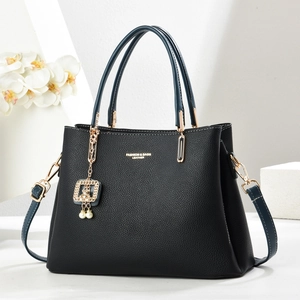 Elegant black lychee leather handbag with golden hardware and a pearl chain pendant