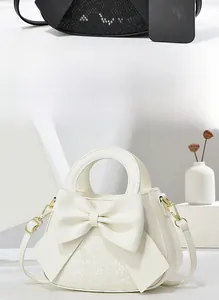 Détail du sac blanc en cuir avec texture serpent et nœud décoratif géant sur le devant