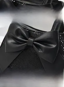 Détail du sac à main noir en similicuir avec motif serpent et grand nœud décoratif