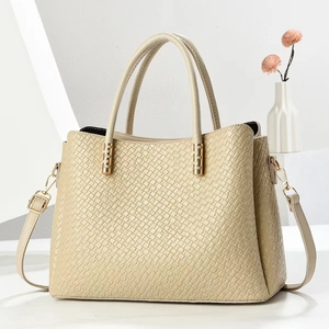 Detail of beige textured tote bag with golden hardware and adjustable crossbody strap