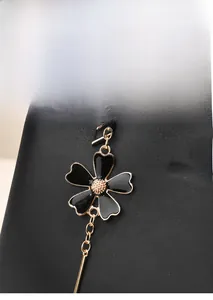 Detail of elegant gold hardware pendant and floral charm on high-quality black leather bag