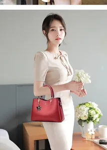 Close-up of a dark red leather handbag featuring a gold ring buckle and a black flower charm