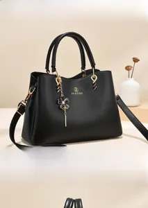 Close-up of black lychee leather handbag with gold hardware and floral charm detail