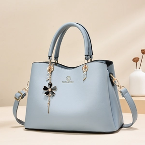 Light blue faux leather handbag with flower pendant and adjustable shoulder strap