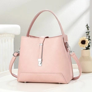 Detail of pink pebbled leather handbag featuring silver hardware and protective metal feet