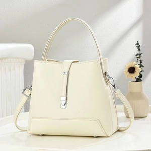 Close-up of cream faux leather handbag with silver metal buckle and stone decor
