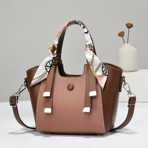 Detail of a brown leather tote bag with twill fabric panel and a silk scarf wrapped handle