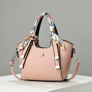 Detail of pink lychee leather crossbody bag with decorative scarf and silver hardware
