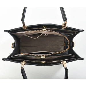 Interior view of black leather tote bag showing multiple compartments and golden zippers