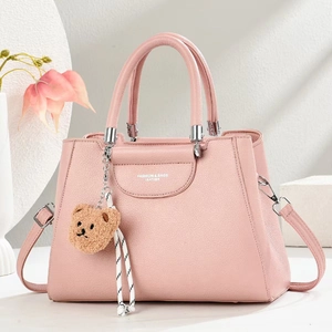 Close-up of pink lychee leather handbag with silver hardware and a cute bear charm