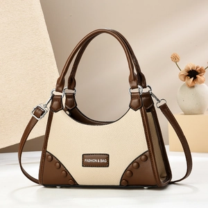 Detail of color-block faux leather bag with litchi texture and metal rivets on corners