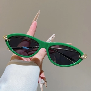 Detail einer grünen Katzenaugen-Sonnenbrille mit goldener Knoten-Metallverzierung