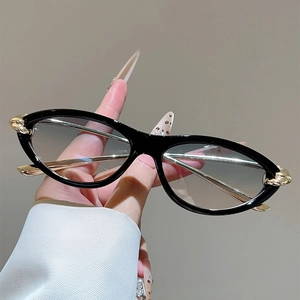 Detail einer Cat-Eye-Sonnenbrille mit goldenen Kettenbügeln und grauem Verlauf