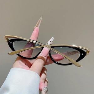 Detailaufnahme der Katzenaugen-Sonnenbrille mit goldfarbenen Bügeln und Verlaufsgläsern