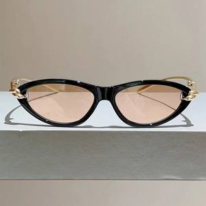 Detailansicht der Cat-Eye-Sonnenbrille mit goldenem Kettenknoten auf schwarzem Rahmen