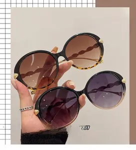 Detail of round oversized sunglasses with gold leaf decor and wave-shaped temples
