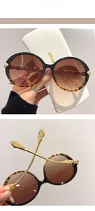 Detail of round sunglasses with leopard print frame and golden leaf-engraved temples