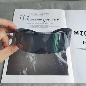 Détail de lunettes de soleil visière cyberpunk gris foncé devant un magazine de mode