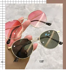 Detail of round sunglasses with pink gradient and dark green lenses in gold metal frames