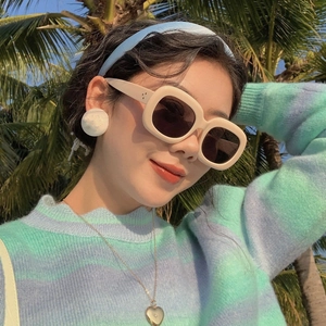 Lunettes de soleil ovales blanc crème pour femmes dans un cadre de vacances à la plage