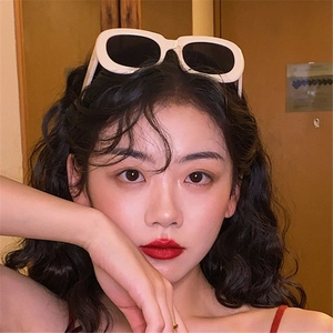 Lunettes de soleil ovales blanc crème portées comme accessoire de cheveux par un modèle