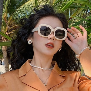 Lunettes de soleil carrées blanc crème avec perles et blazer orange en décor tropical