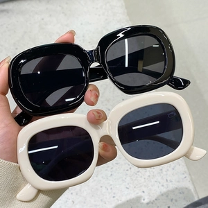 Détail de lunettes de soleil vintage ovales en noir et blanc crème tenues à la main