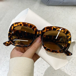 Détail de lunettes de soleil en écaille ambre avec verres bruns et étui en cuir