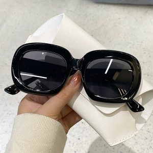 Gros plan de lunettes de soleil carrées noires rétro avec verres gris en vue tenue