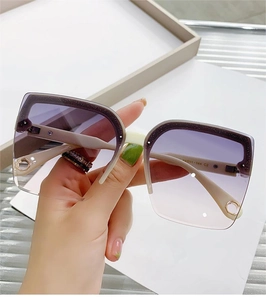 Detailed hand-held view of oversized square sunglasses with purple gradient lenses