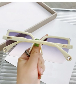 Detail of cream square rimless sunglasses with purple gradient lenses and gold metal accents