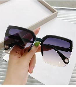 Close-up of purple gradient lenses and gold metal details on square rimless sunglasses