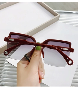 Detail of square oversized rimless sunglasses with dark red frame and gradient purple lens