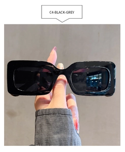 Detail view of black rectangular retro sunglasses with grey lenses and a glossy frame