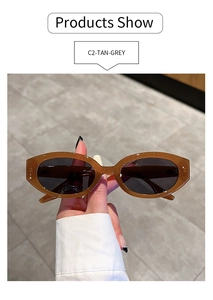 Detail view of oval tan tortoiseshell sunglasses with dark gray lenses in hand