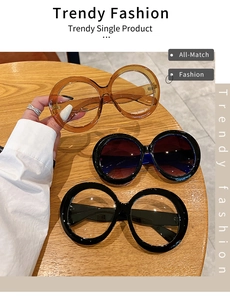 Three variants of oversized round sunglasses displayed on a warm wooden table
