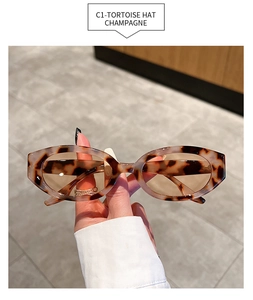 Detail of tortoise shell oval sunglasses frame with champagne lenses in hand
