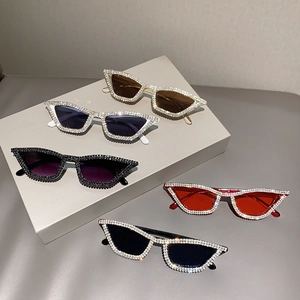 Cat eye rhinestone sunglasses in five colors displayed on geometric pedestals