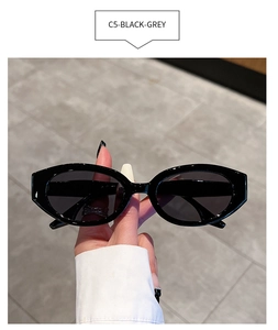 Detail view of oval retro sunglasses with glossy black frame and dark grey lenses