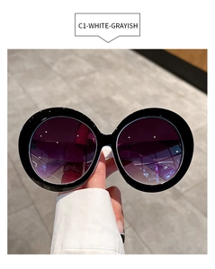 Detail showing oversized round sunglasses with glossy black frames and gradient lenses