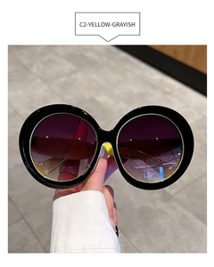 Detail of round oversized sunglasses featuring purple gradient lenses and yellow inner arms