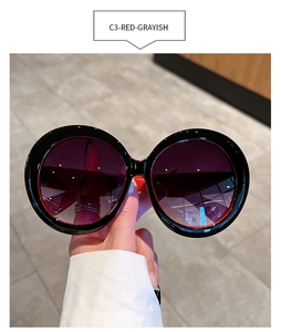 Detailed close-up of round oversized sunglasses with black frame and red purple gradient lens