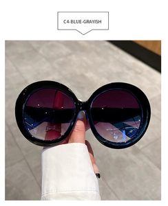 Detail of round oversized black frame sunglasses with blue-grayish gradient lenses