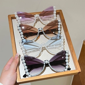 Detailed macro view of butterfly oversized sunglasses with pearl-encrusted frames and gradient lenses