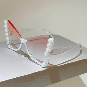 Macro detail of cat eye sunglasses featuring pink gradient lenses and pearl-encrusted frame