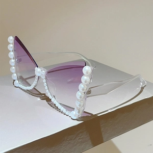 Close-up of butterfly sunglasses featuring pearl-encrusted frames and purple gradient lenses