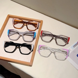 Five pairs of cat-eye anti-blue light glasses in varied contrast colors on a wooden tray